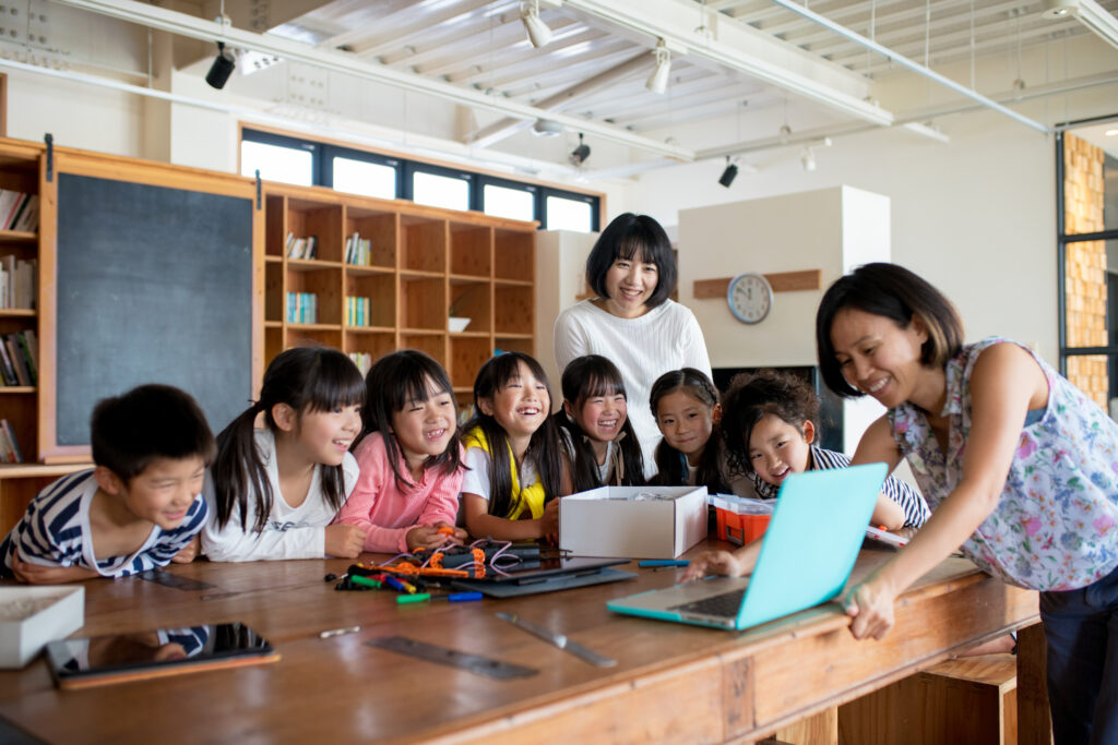 Group of children and teachers looking at laptop